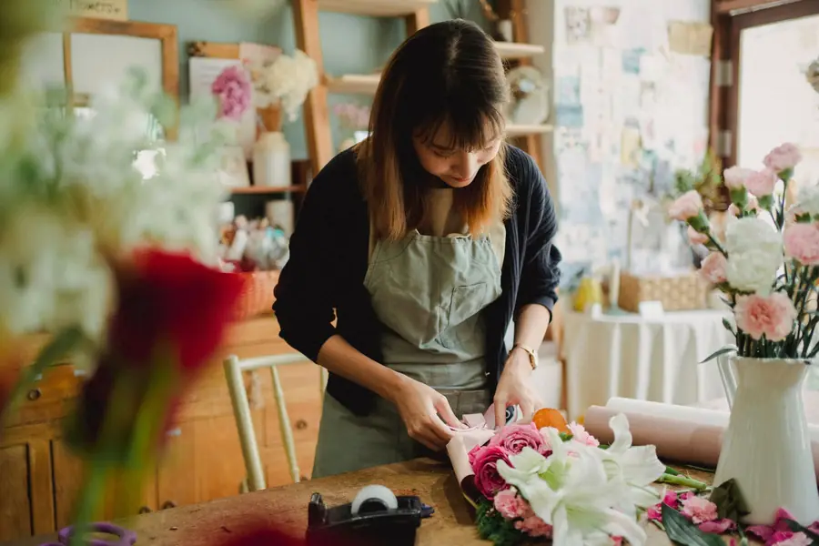 A florist wrapping a fresh bouquet at her workbench